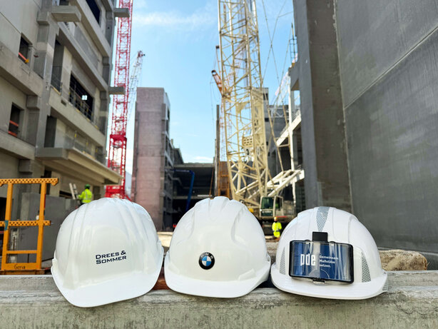  Helmets with the logos of the companies involved in front of the construction site